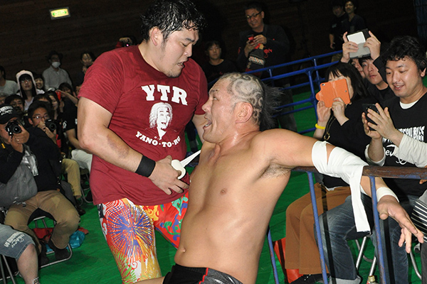 Toru Yano tapes Minoru Suzuki to the guardrail.