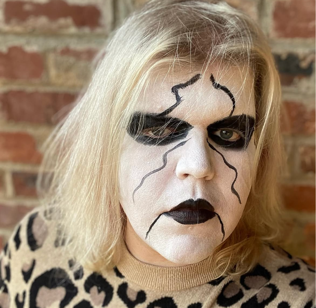 Colette, a blonde-haired woman in a cheetah print sweater, wears a full face of Sting makeup.